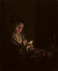 A candlelit interior with a young man seated at a table, lighting his pipe