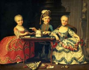 A boy and two girls building a house of cards with other games by the table